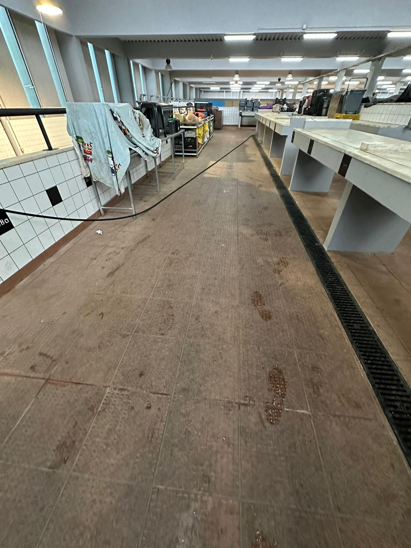 Corredor de pavimento cerâmico com marcas de pegadas e sujidade, antes da limpeza.