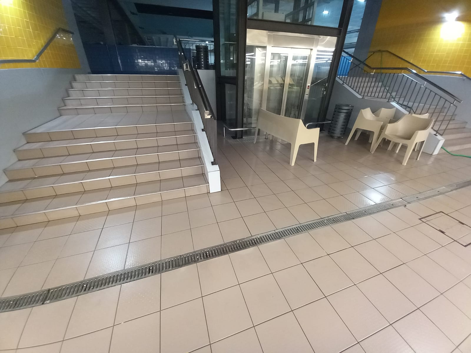 Escadas e pavimento cerâmico claro junto ao elevador do Mercado Municipal da Póvoa de Varzim.