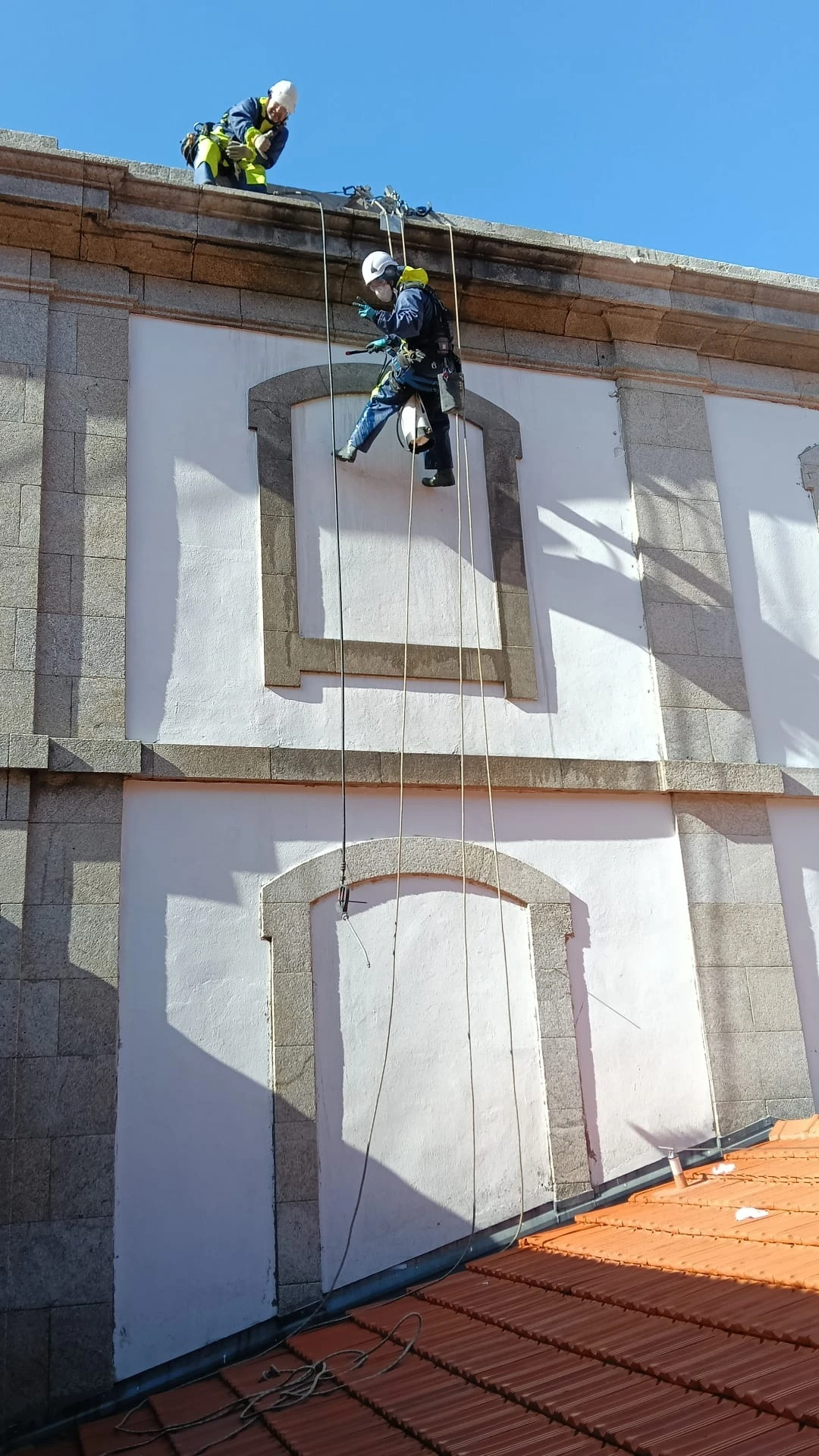 Técnicos de acesso por corda da AREALIMPA a trabalhar na fachada em granito da Alfândega do Porto