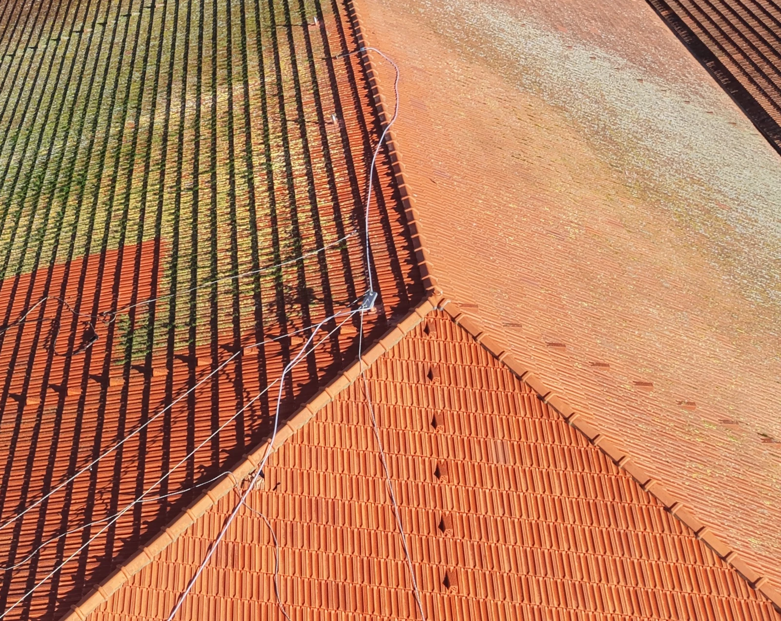Vista de drone do telhado da Alfândega do Porto durante a limpeza da AREALIMPA, com zonas de telha já limpas ao lado de zonas ainda escuras