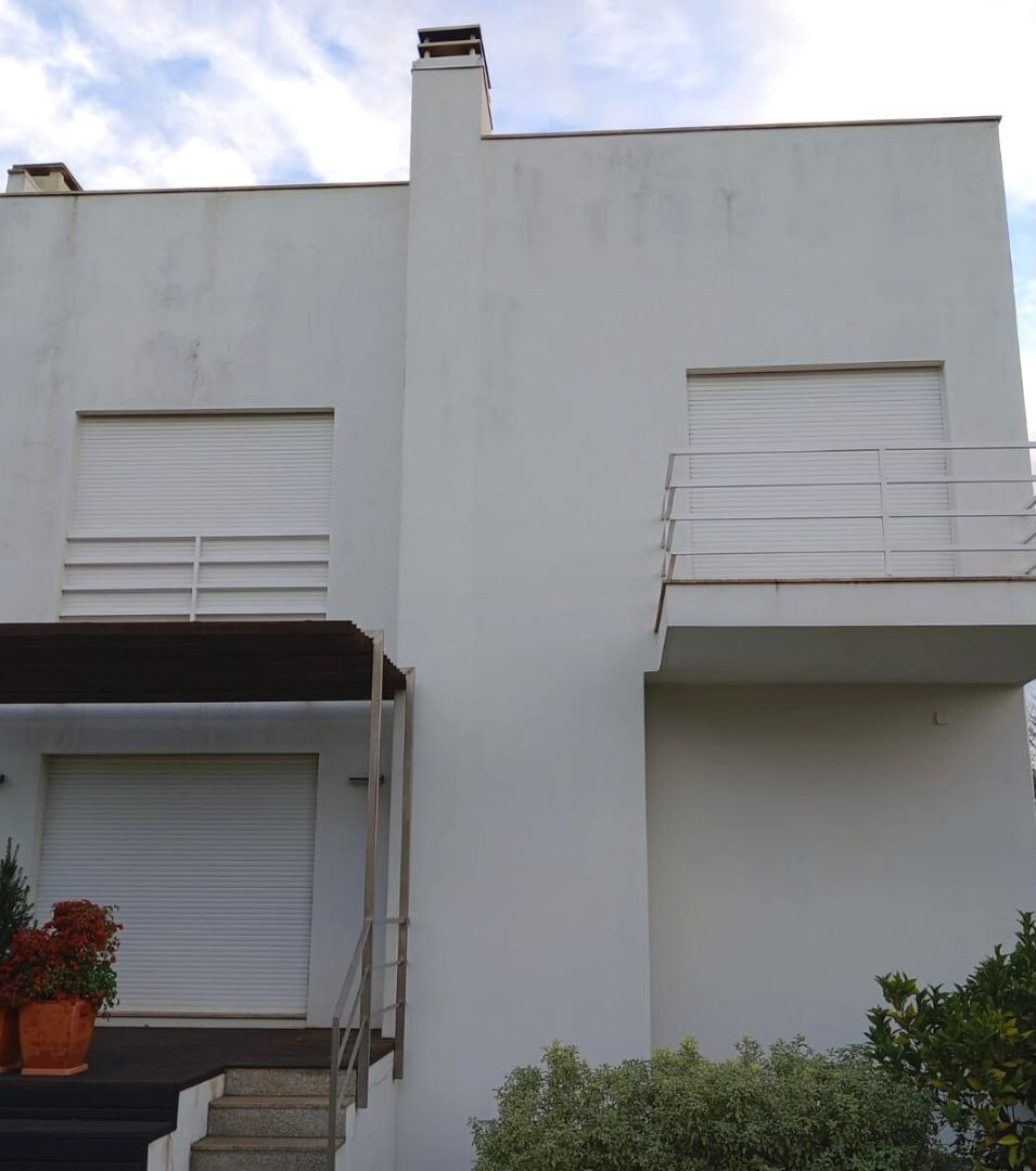 Fachada de moradia com manchas escuras de humidade e sujidade na parede.