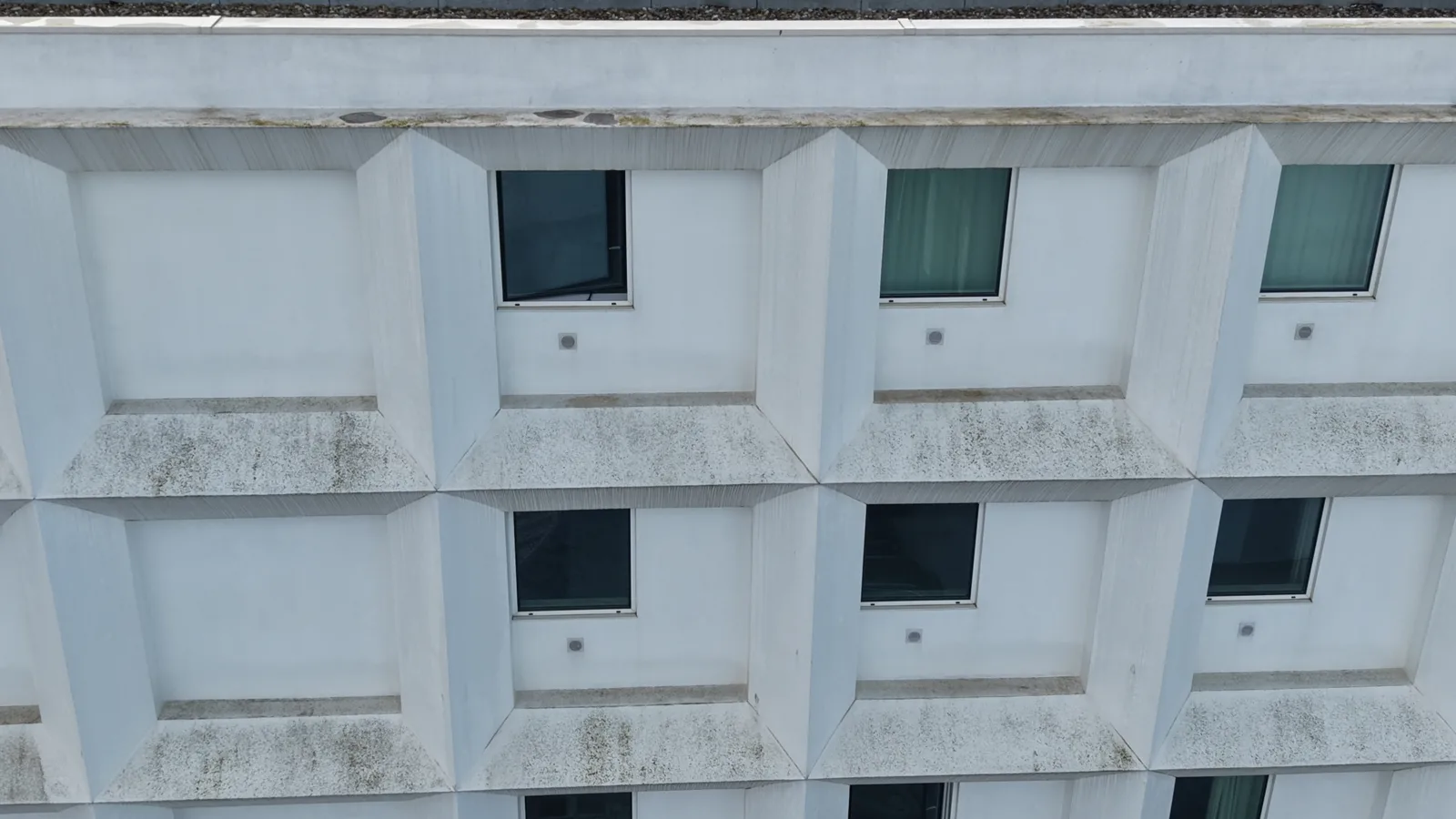 Vista de drone da fachada principal do Hotel B&B Vila do Conde antes da lavagem, com verdete e sujidade escura nos parapeitos dos módulos salientes