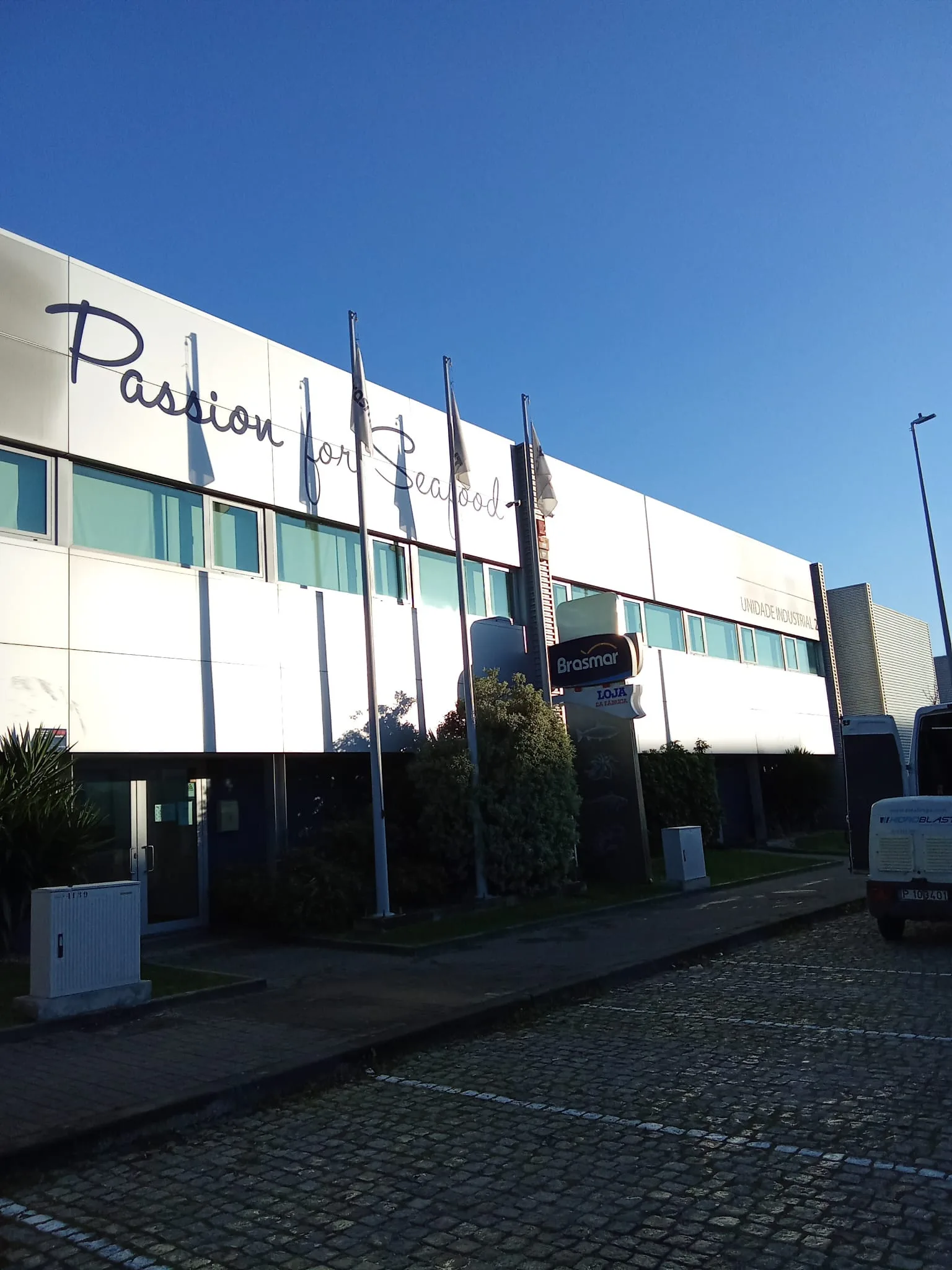 Portão seccionado branco do cais da Unidade Industrial 2 da Brasmar, com placa da Securitas