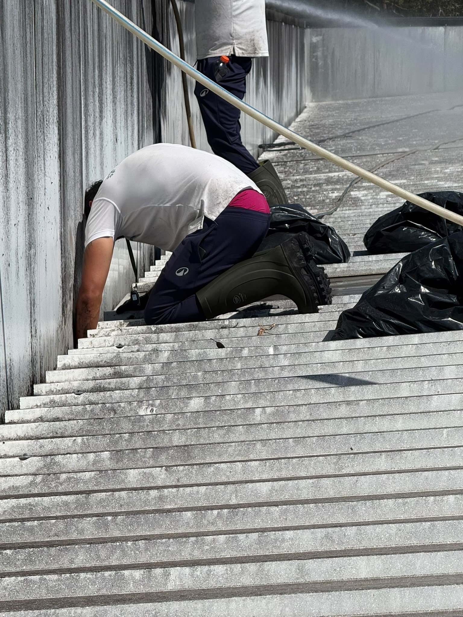 Operador da Arealimpa a limpar caleira industrial à mão em Cantanhede