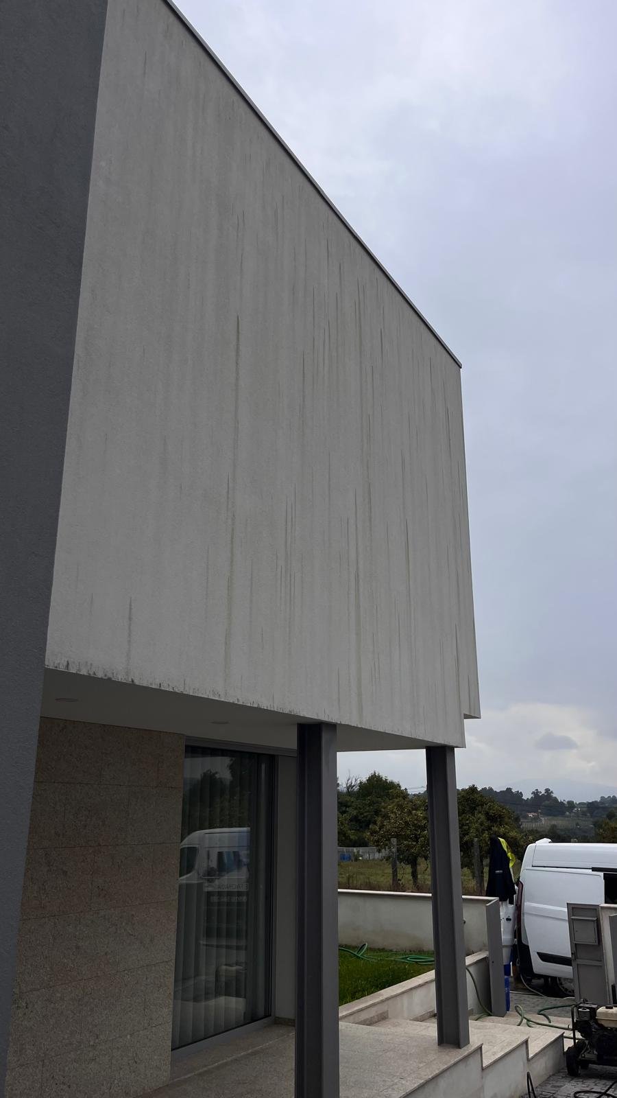 Empena em capoto de moradia em Braga com riscas verdes de algas antes da lavagem