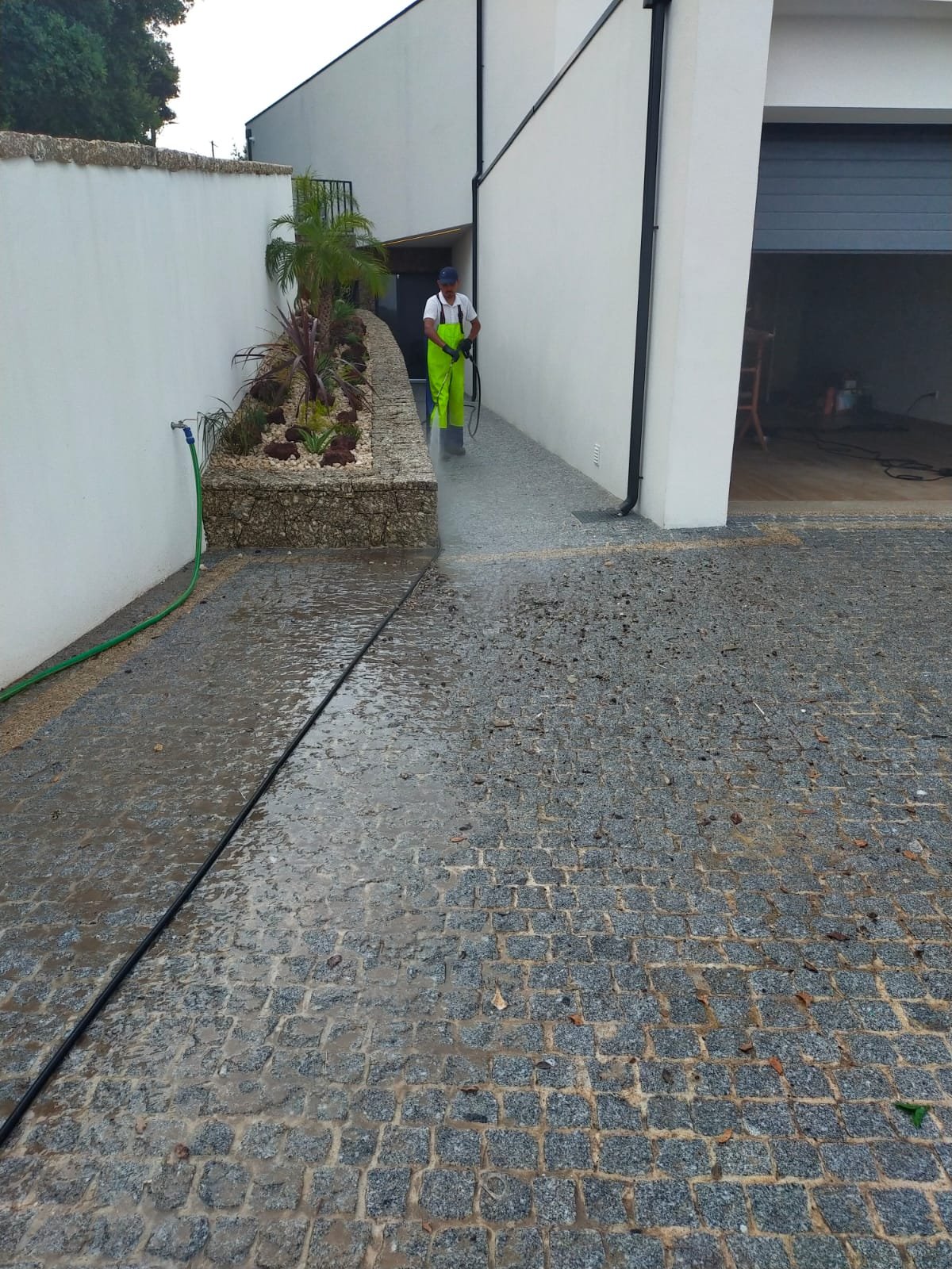Operador da Arealimpa a lavar a passagem em granito junto à moradia em Guimarães