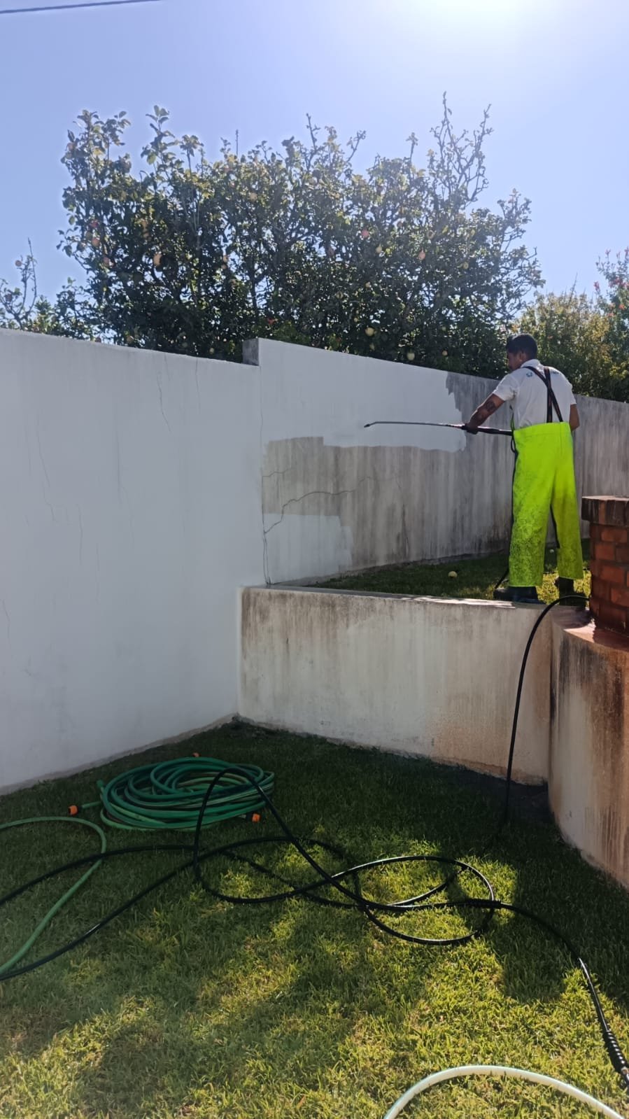 Muro na Marinha Grande a meio da lavagem, com parte branca limpa e parte cinzenta