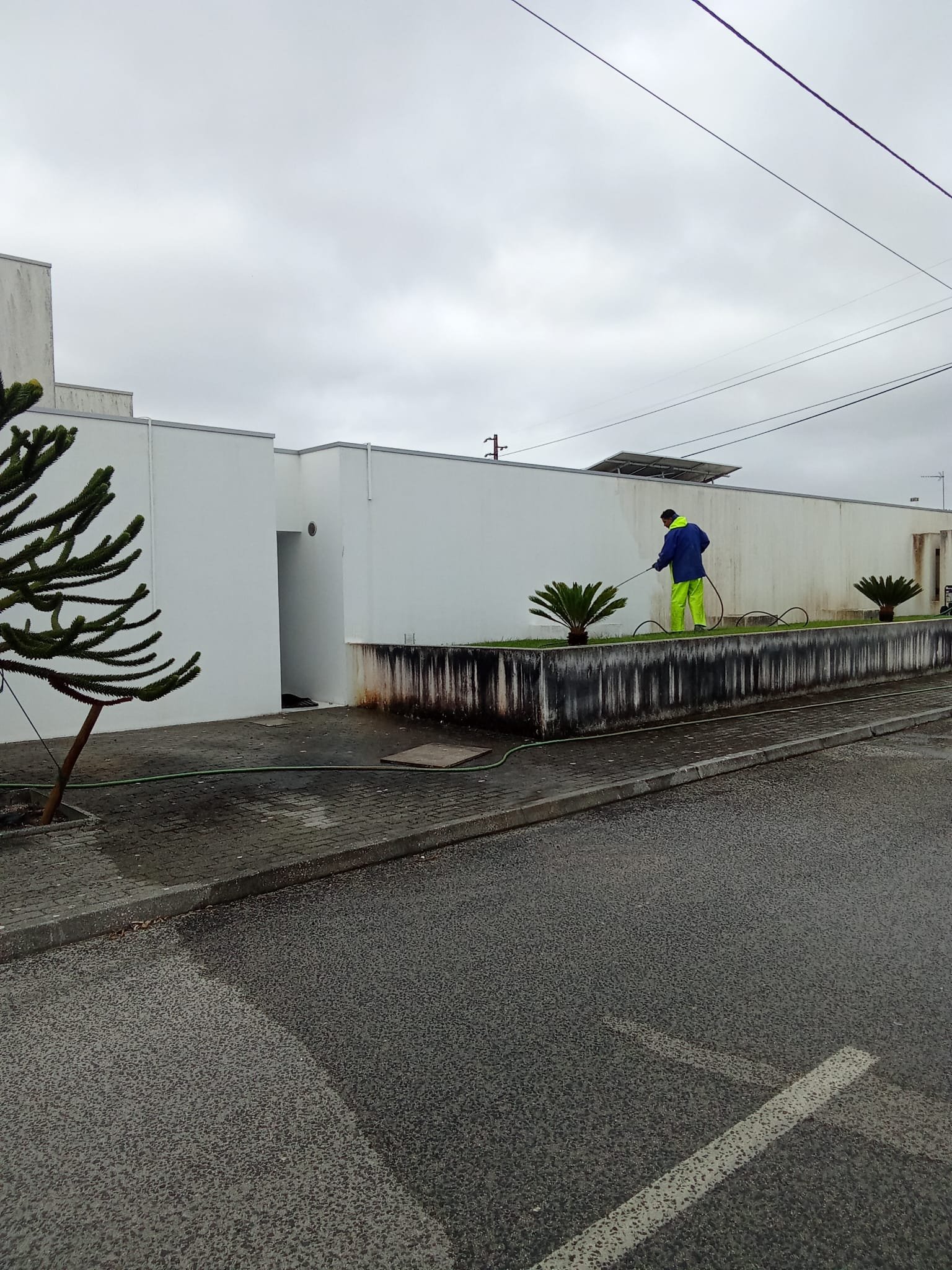 Operador a lavar fachada em capoto virada para a rua na Marinha Grande