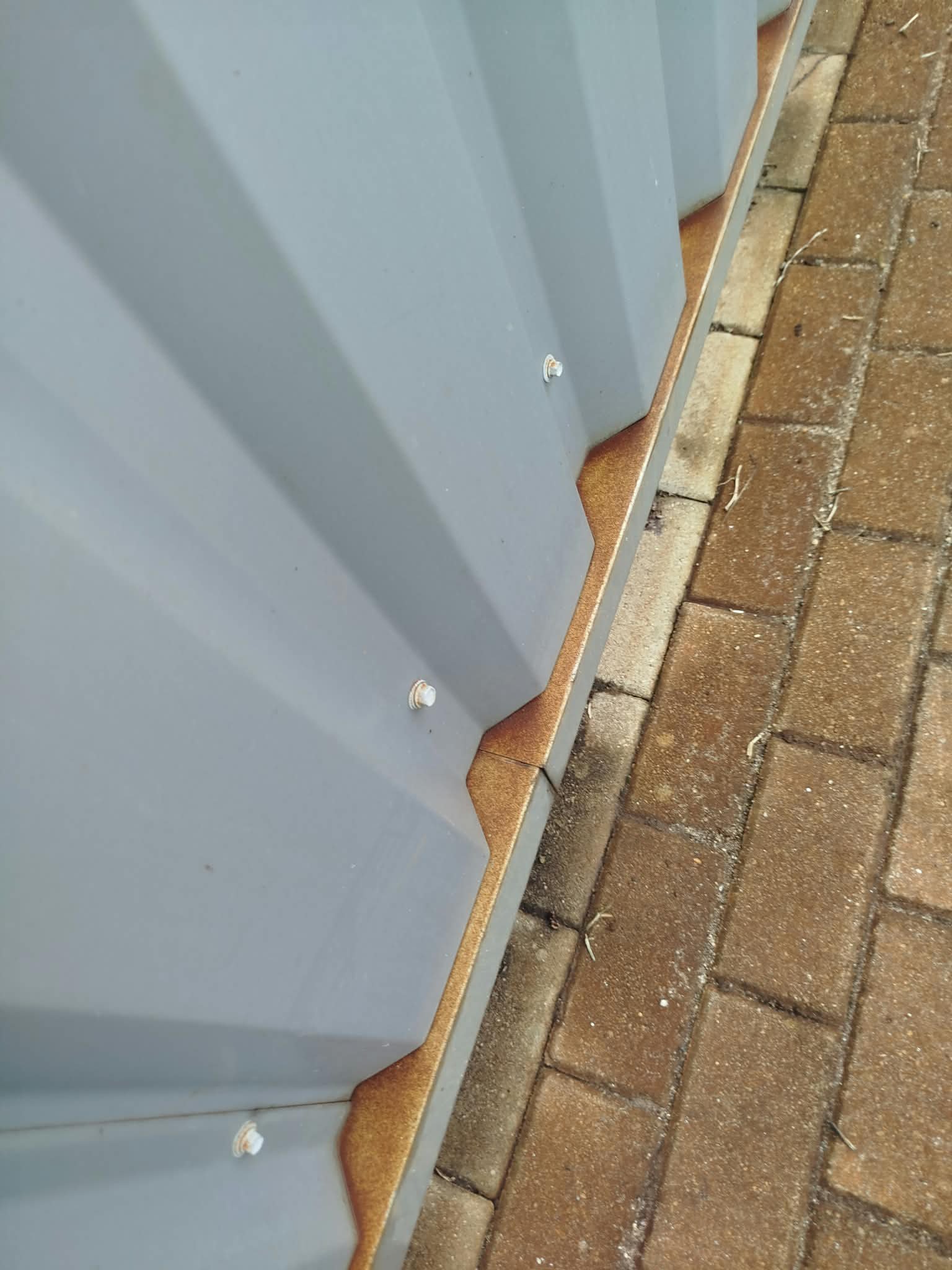 Chapa canelada e pavimento em blocos com manchas de ferrugem em Santo Tirso