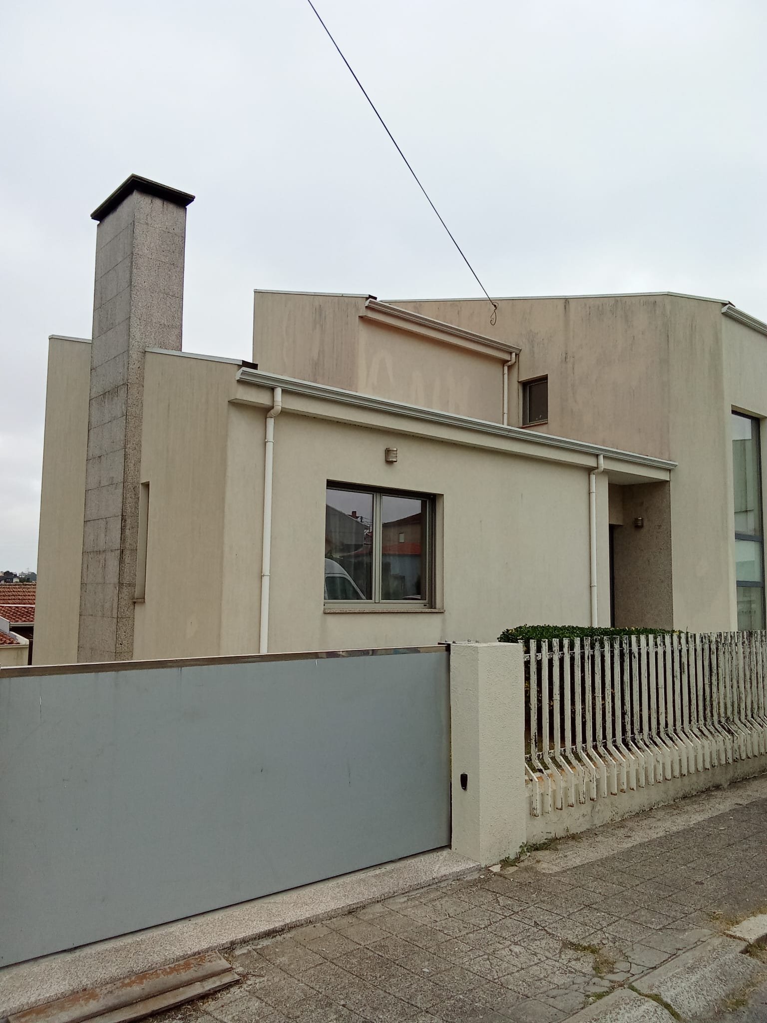 Lateral da moradia em Gaia junto à chaminé de granito com fachadas sujas