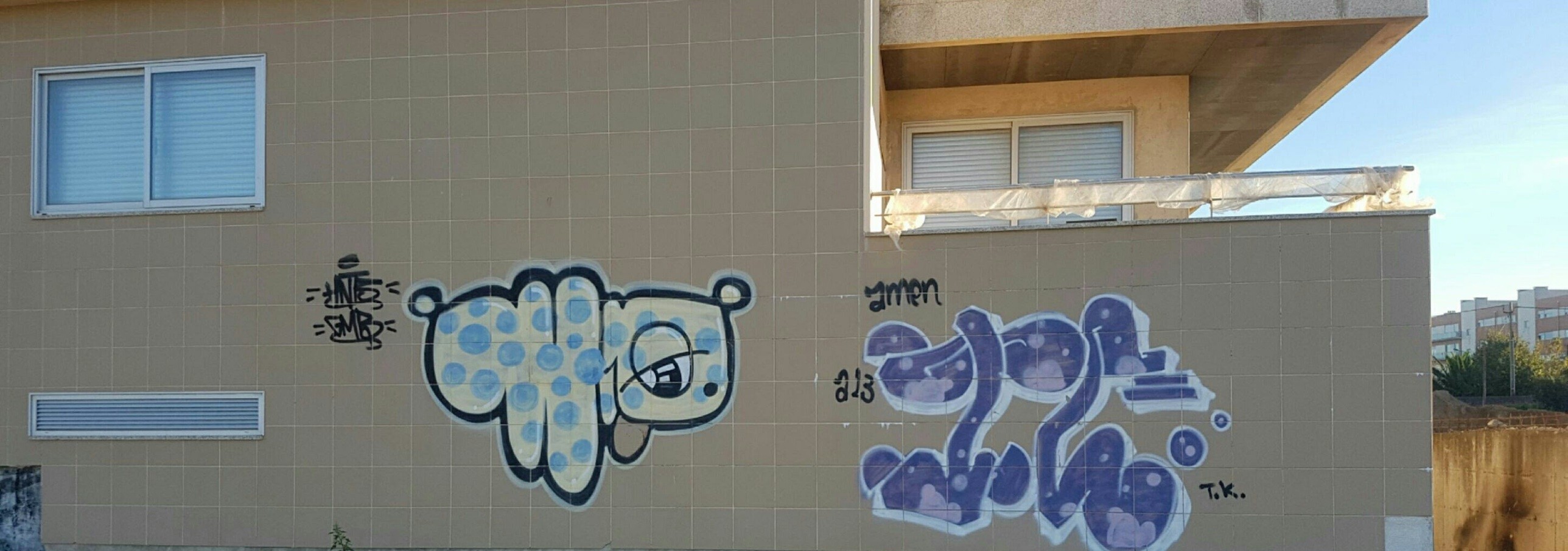 Fachada de prédio em revestimento cerâmico em Vila do Conde com dois graffiti de grande dimensão