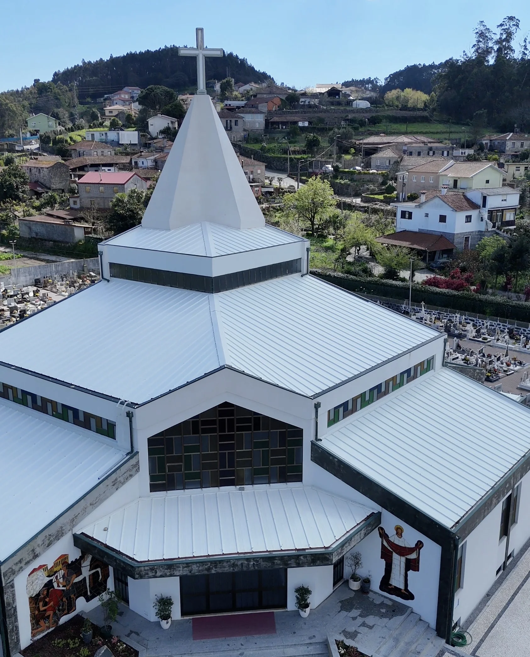 Frente da Igreja de Brufe vista de cima depois da lavagem, com as coberturas metálicas claras, o vitral e a entrada
