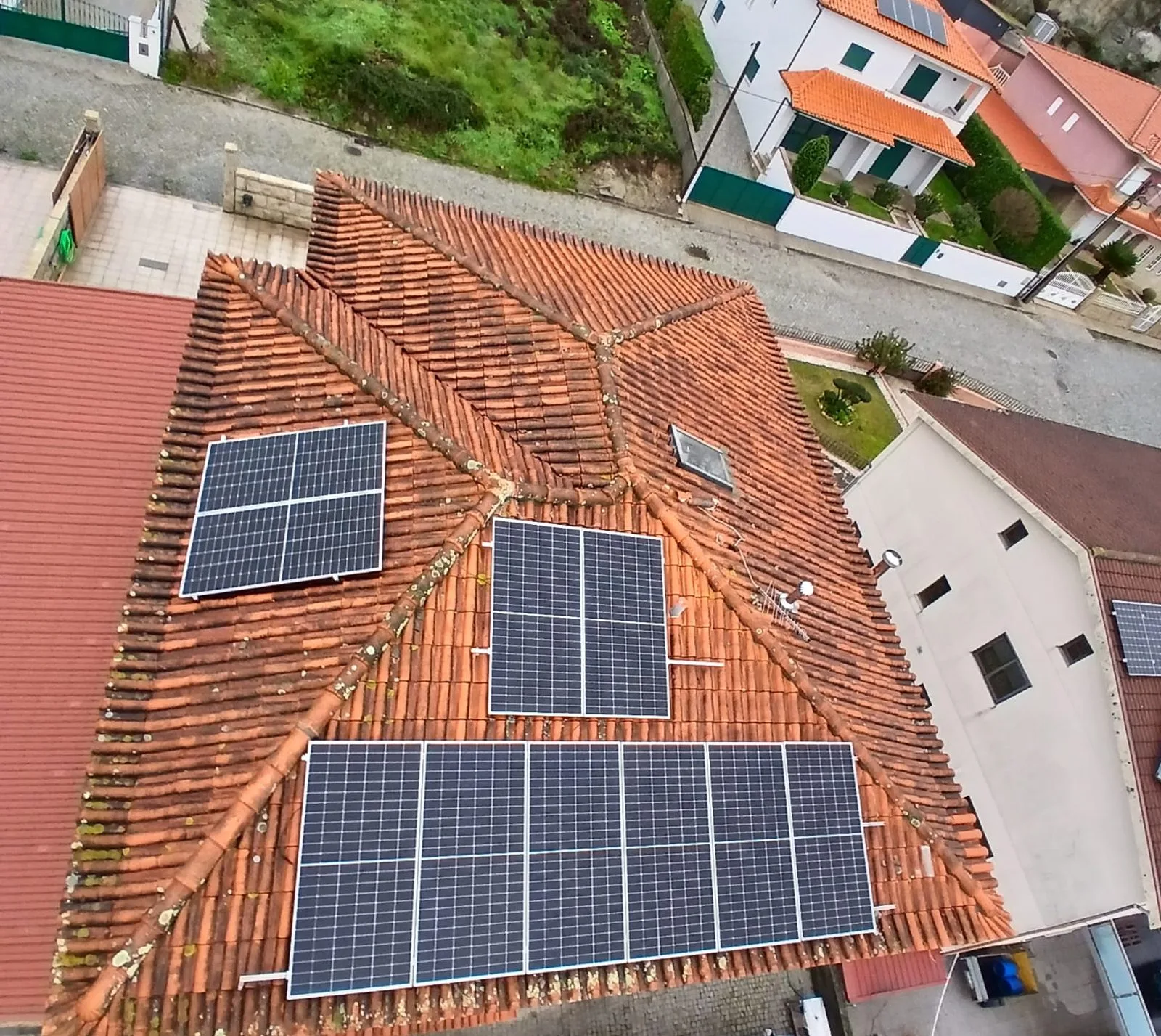 Vista de drone de telhado de moradia em Amarante com painéis solares e telha escurecida por musgo e líquenes antes da limpeza SoftWash da AREALIMPA