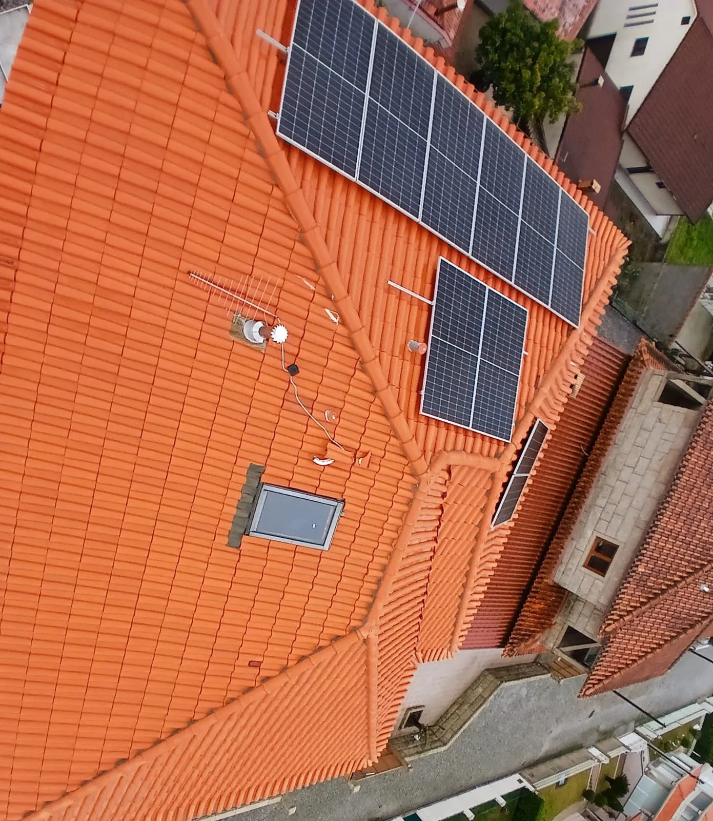 Vista de drone, mais aproximada, do mesmo telhado em Amarante com a telha limpa entre os painéis solares depois da limpeza SoftWash da AREALIMPA