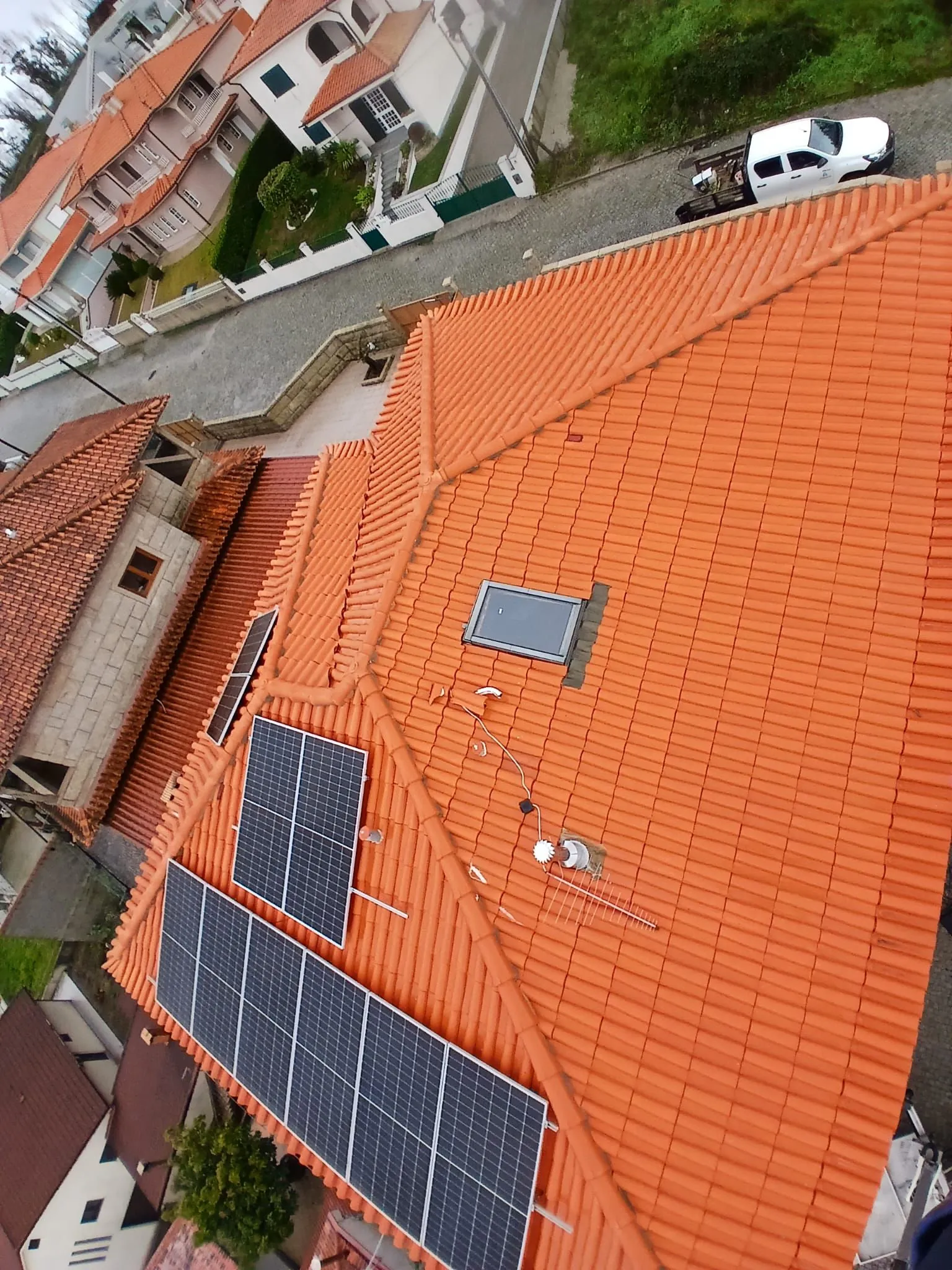 Vista de drone do mesmo telhado em Amarante, com a telha cerâmica mais clara, painéis solares e claraboia, depois da limpeza SoftWash da AREALIMPA