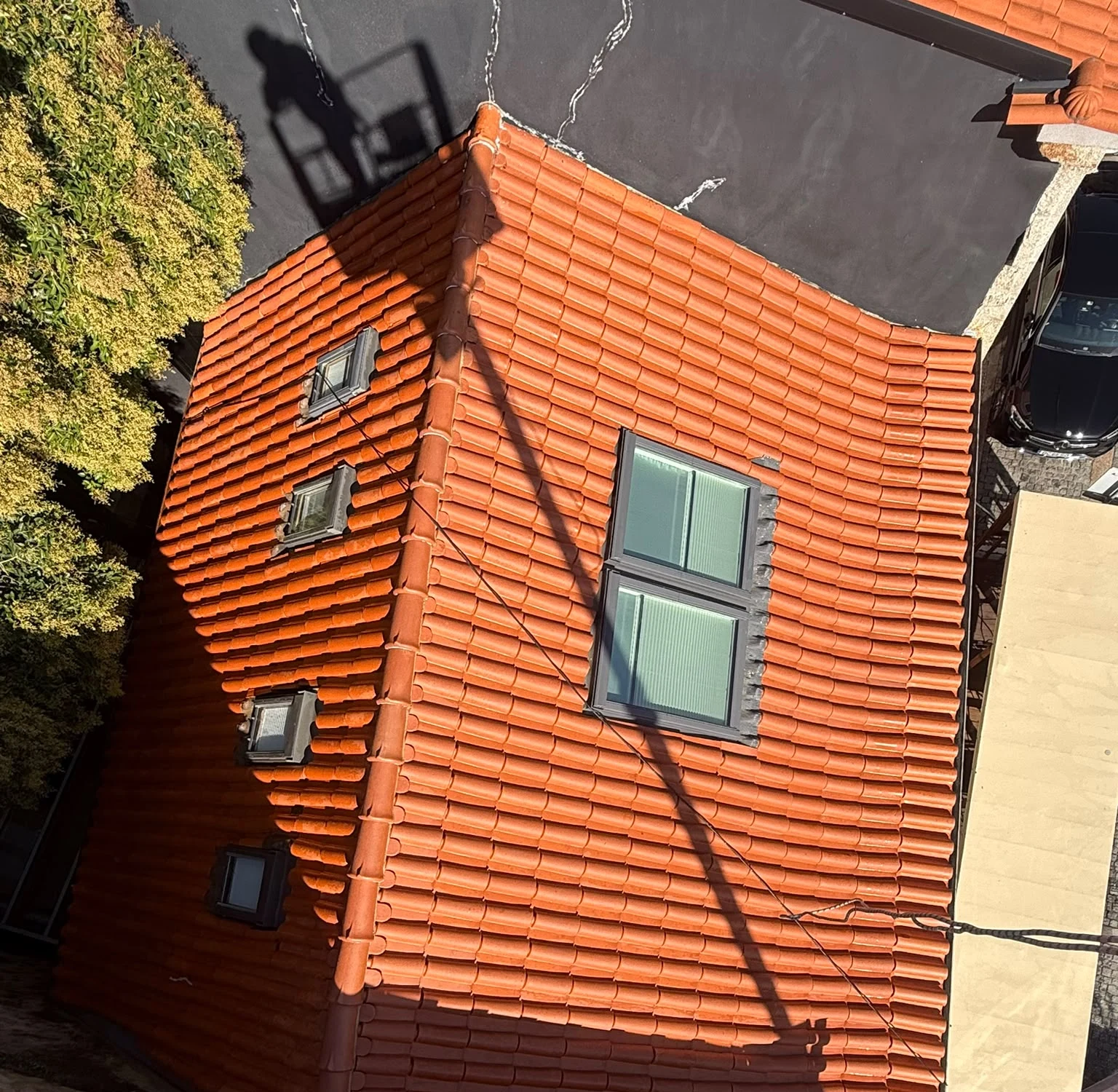 Telhado em telha cerâmica no centro de Barcelos visto de cima depois da lavagem com SoftWash, com várias águas e claraboias