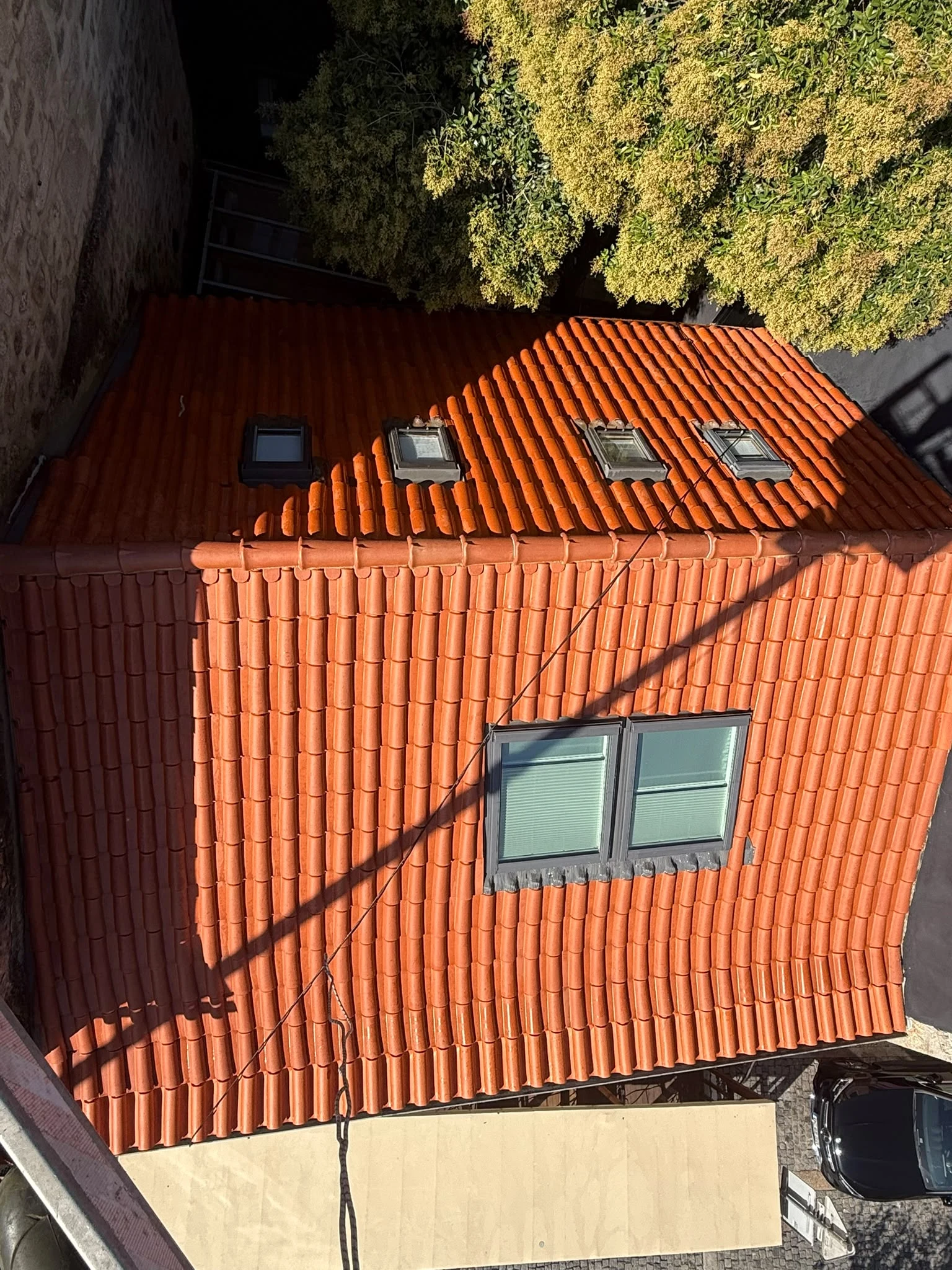 Vista de cima do telhado em Barcelos depois da lavagem SoftWash e da aplicação de hidrófugo, com quatro claraboias e uma janela de telhado dupla