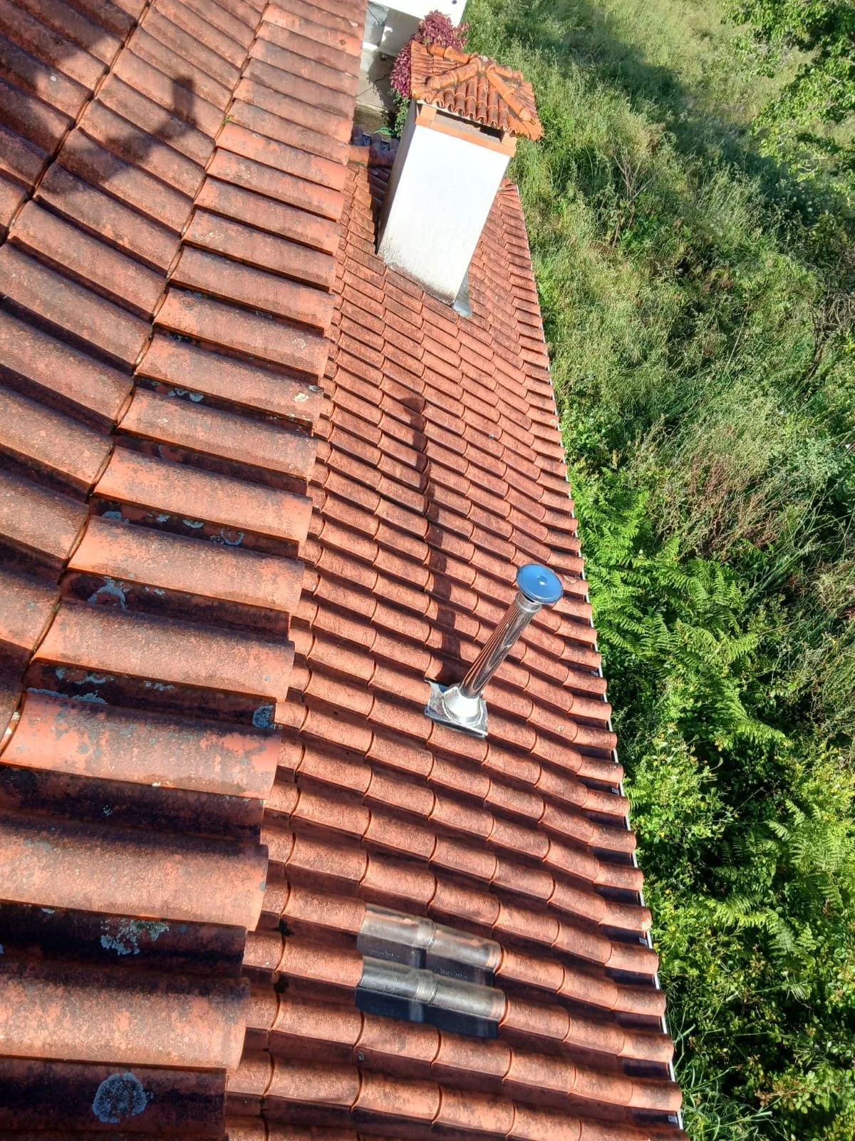 Água de telhado em telha cerâmica de uma moradia em Santa Maria da Feira, com a telha escurecida e manchada de líquenes junto à chaminé, antes da limpeza SoftWash da AREALIMPA
