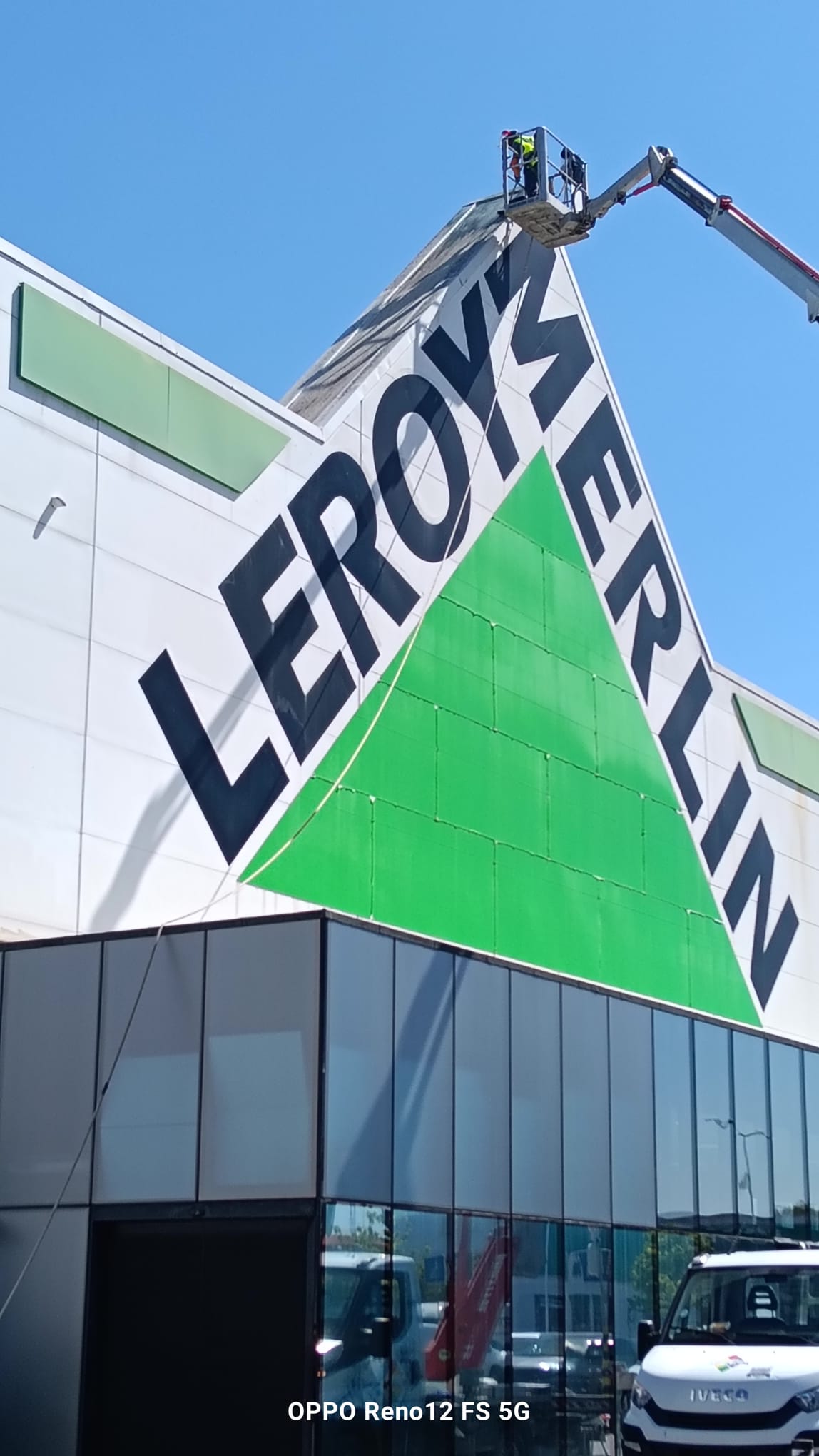 Profissional numa plataforma elevatória junto ao topo da fachada da Leroy Merlin de Matosinhos durante a intervenção