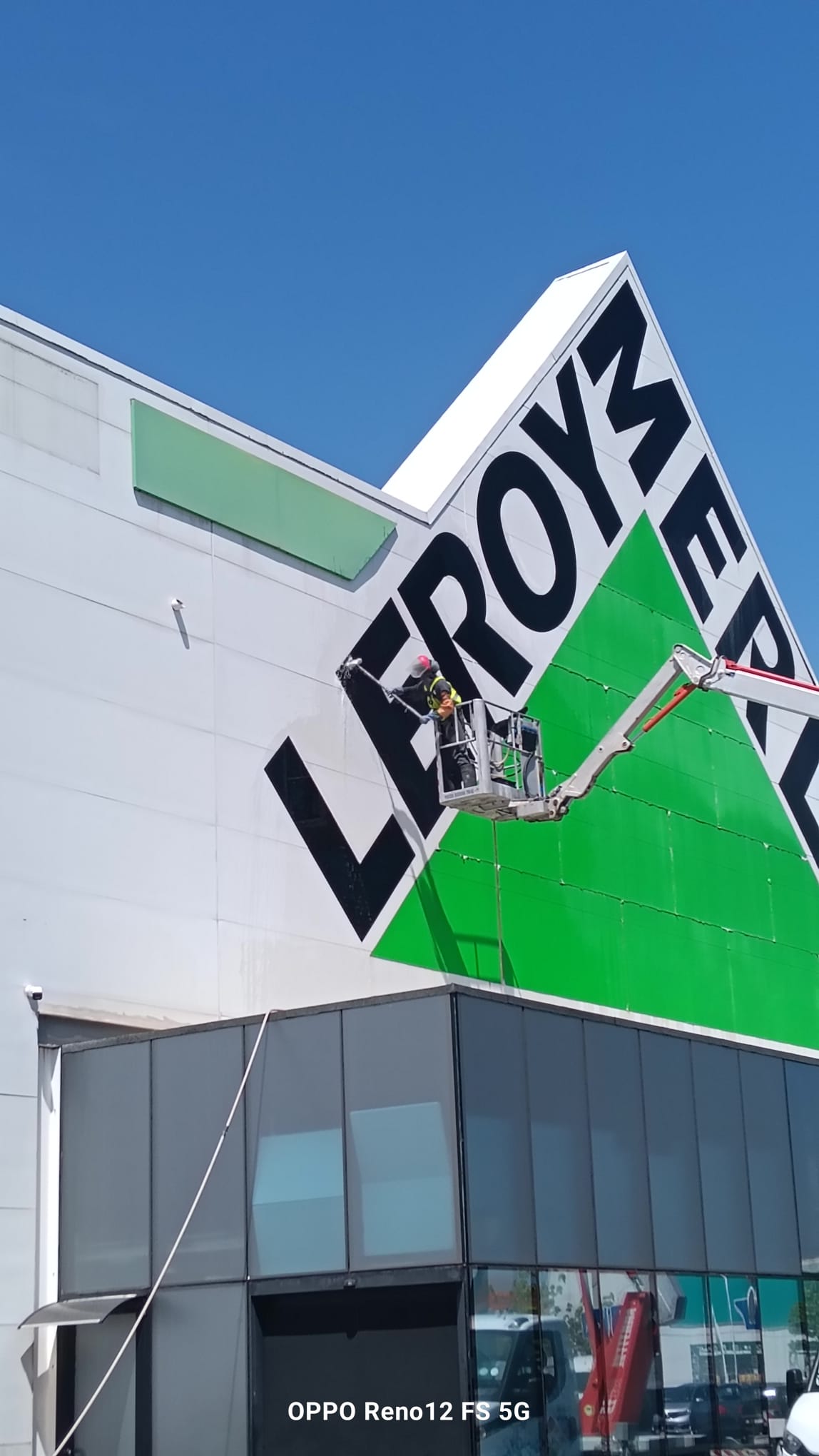 Técnico a lavar a fachada junto ao letreiro da Leroy Merlin de Matosinhos numa plataforma elevatória própria da Arealimpa