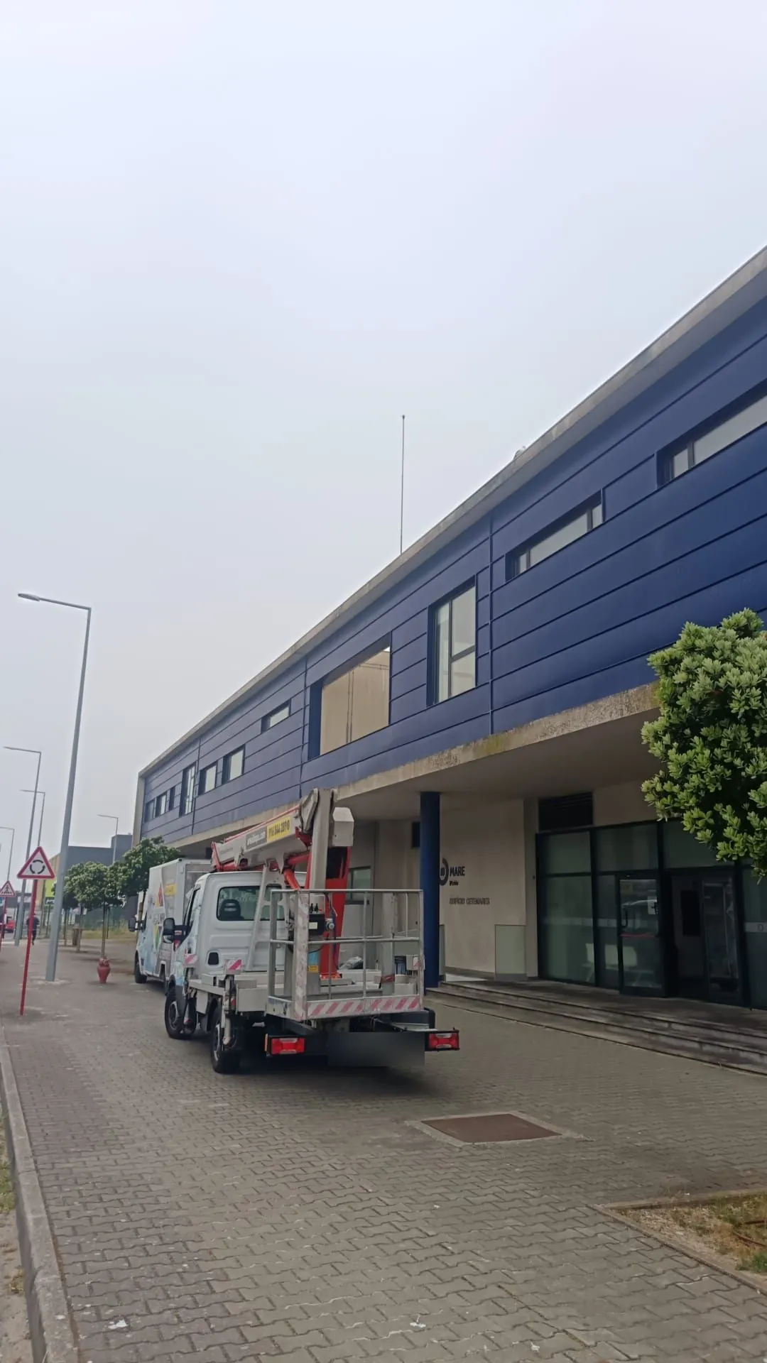 Fachada longa com faixa azul do Instituto Politécnico de Leiria em Peniche, vista da rua, antes da limpeza da AREALIMPA