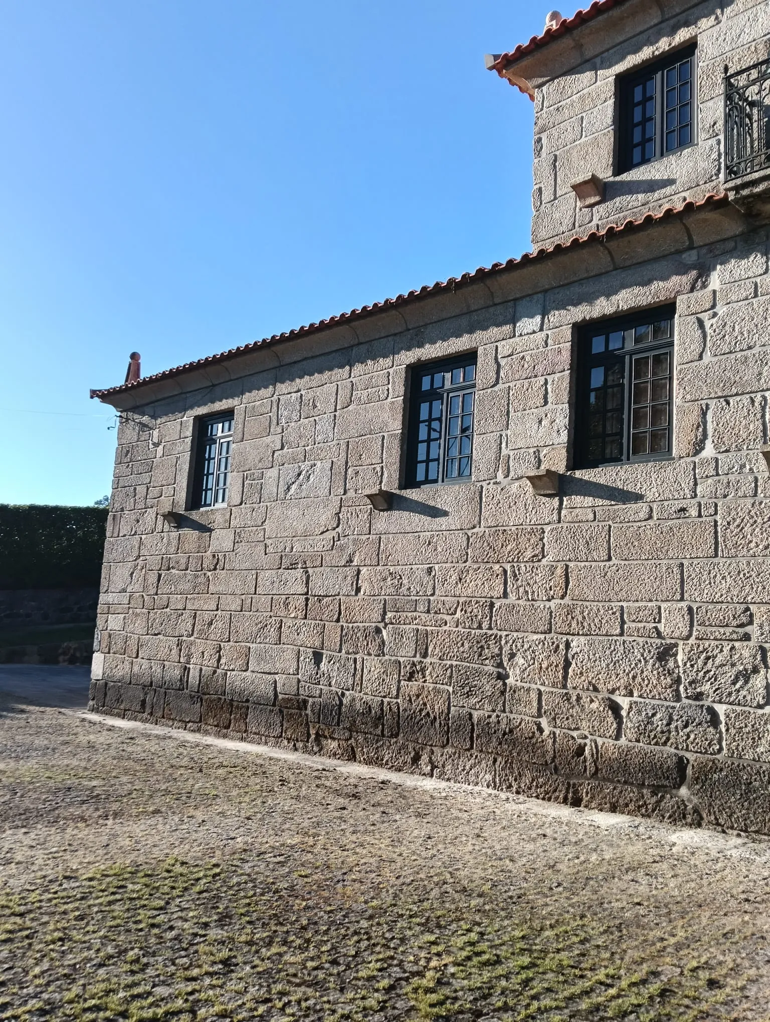 Fachada lateral em granito de um edifício em Penafiel, com a base escurecida, antes da limpeza da AREALIMPA