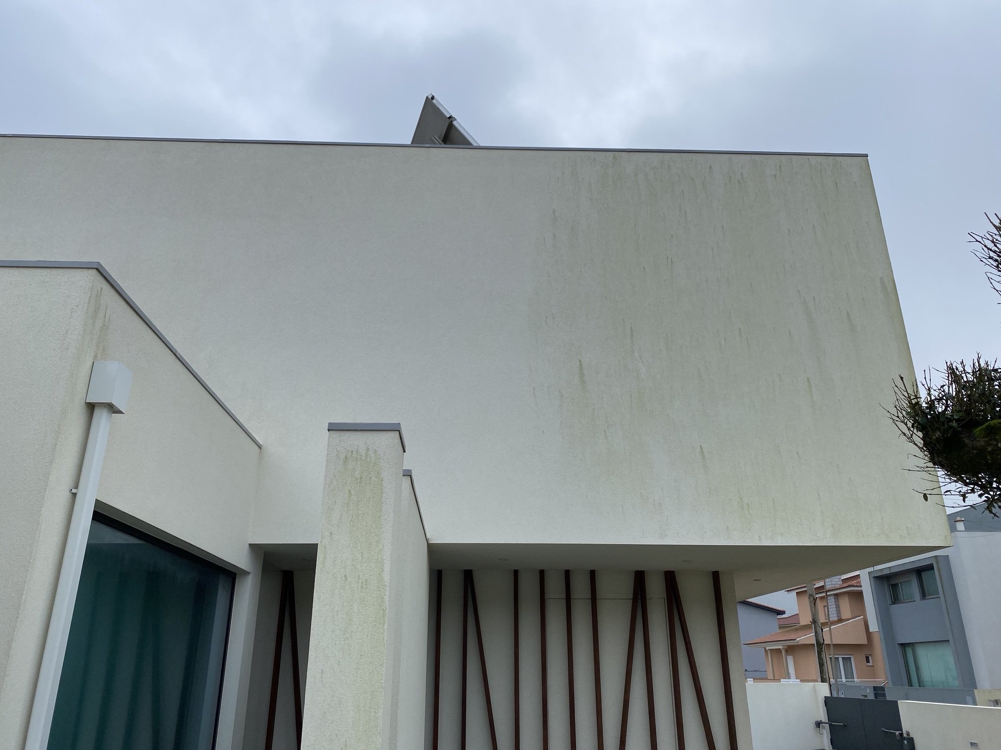 Parede da moradia em Aguçadoura a meio da limpeza, com metade limpa e metade ainda com algas
