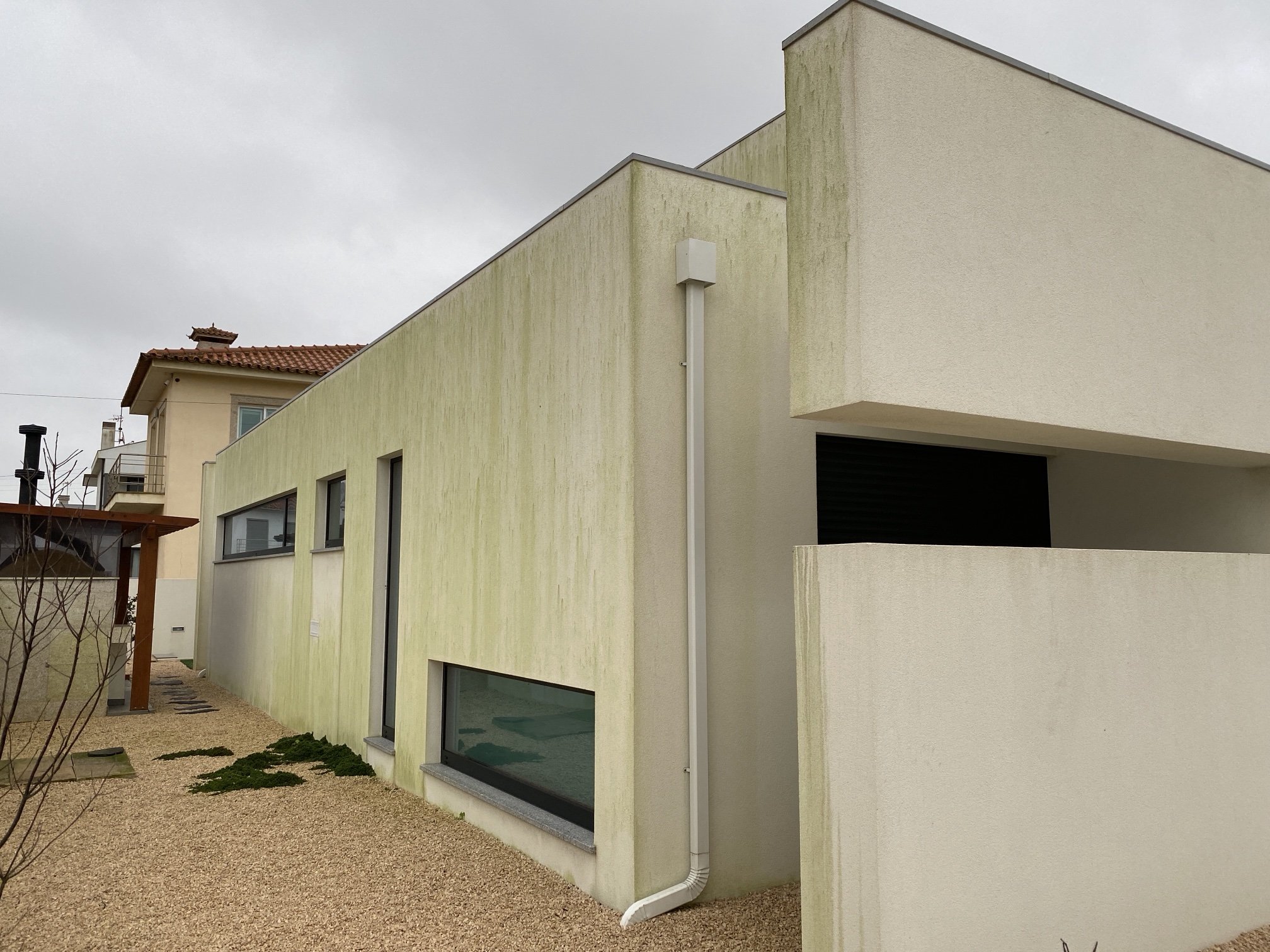 Fachada lateral da moradia em Aguçadoura com escorrências verdes de algas