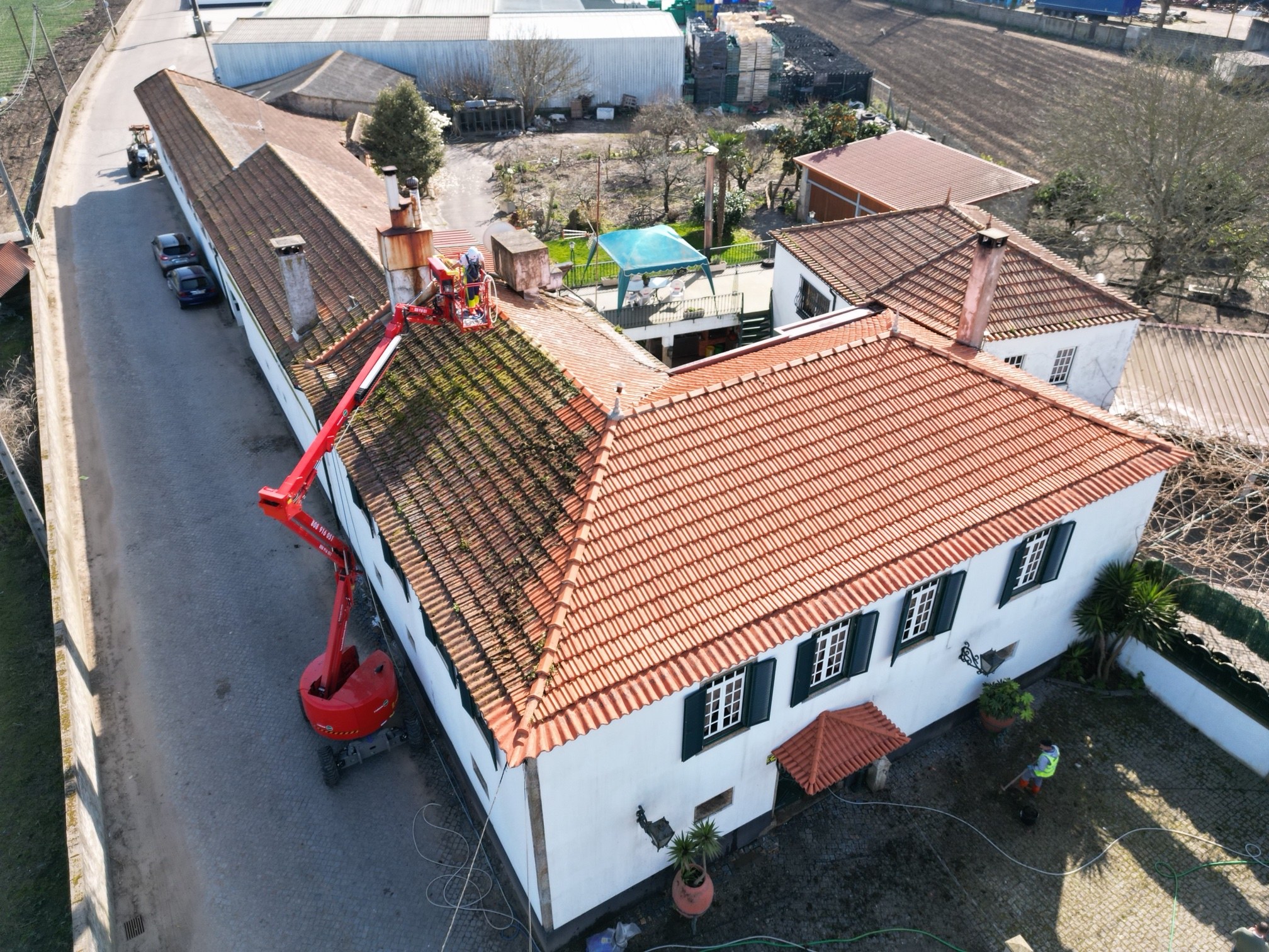 Vista aérea da moradia na Póvoa de Varzim a meio da limpeza, com parte do telhado limpa e parte com musgo