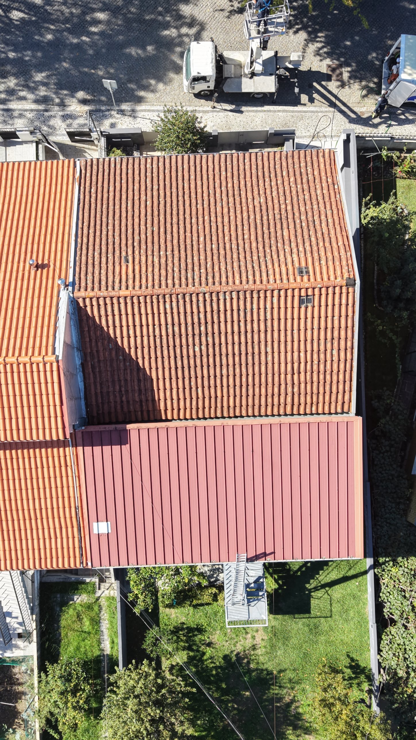 Vista aérea de telhado escuro com líquenes numa moradia geminada em Braga, ao lado de um telhado já renovado