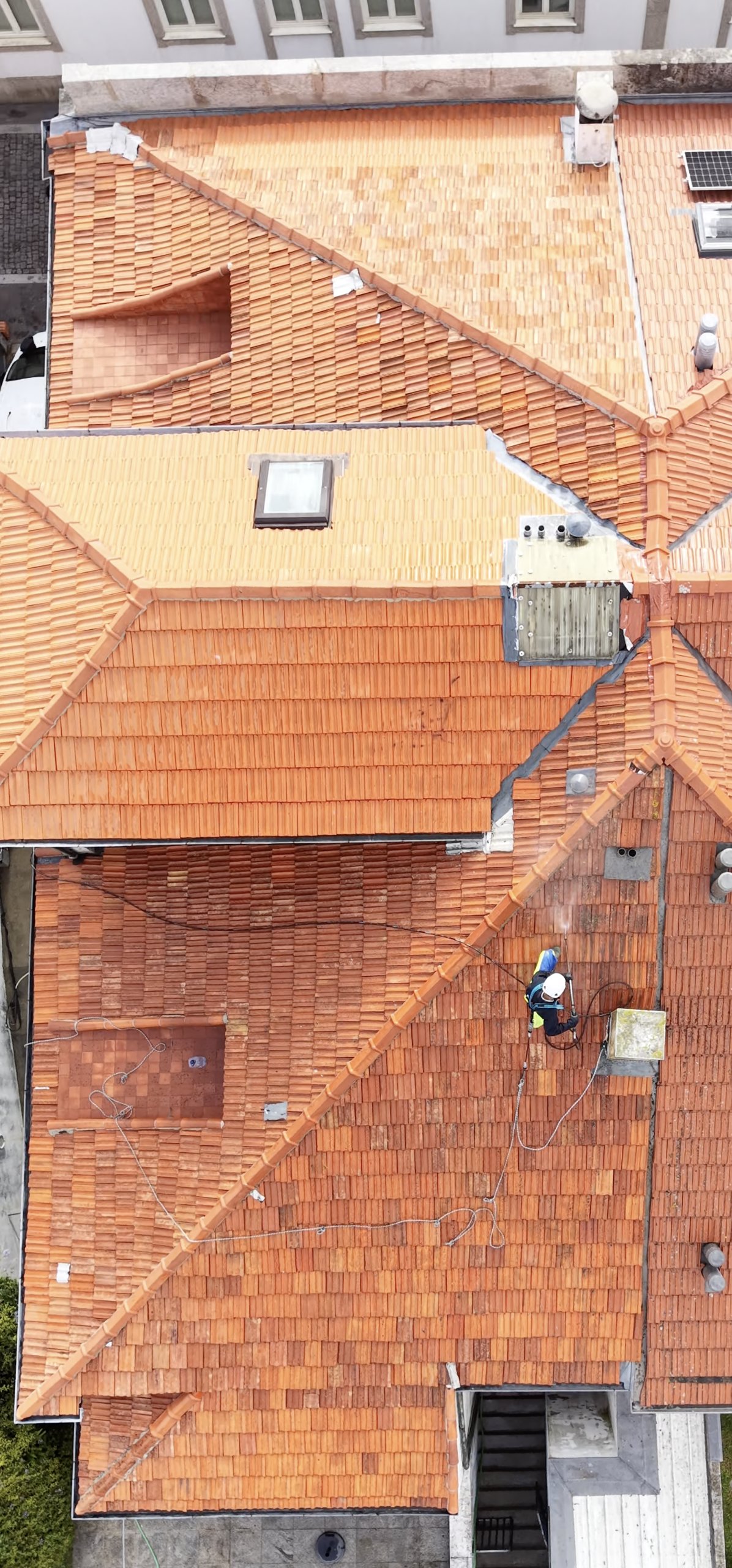Vista de drone do telhado em Leça da Palmeira com a parte de cima já pintada e operador a lavar a parte de baixo
